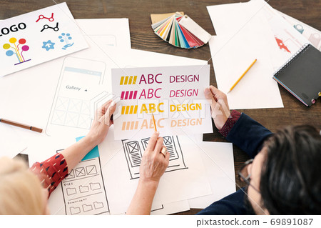 Hands of mature female designer pointing at paper with letters and words Hands of mature female designer pointing at paper with letters and words 69891087