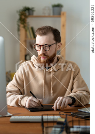Young contemporary serious freelance designer using touchpad and stylus Young contemporary serious freelance designer using touchpad and stylus 69891325