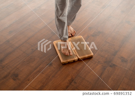 Legs of young active barefoot man in grey sportspants standing on yoga pads 69891352