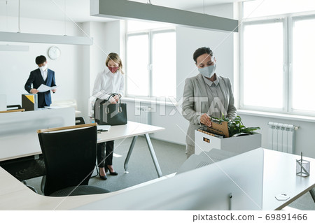 Young business people in formalwear and protective masks taking out supplies 69891466