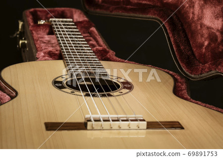 Acoutic guitar sits in red velvet lined case Acoutic guitar sits in red velvet lined case 69891753
