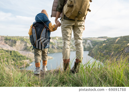 Rear view of young woman and her little son with backpacks holding by hands 69891788