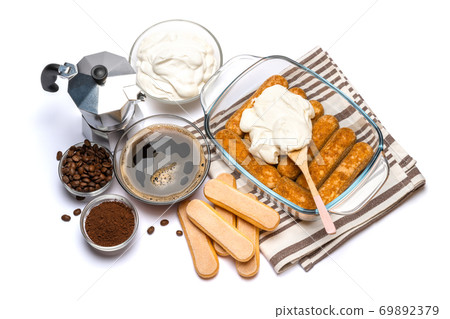 tiramisu dessert cooking - Traditional Italian Savoiardi ladyfingers Biscuits and cream in glass baking dish isolated on white with clipping path 69892379