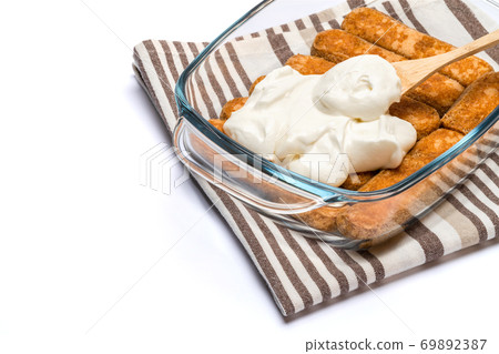 tiramisu dessert cooking - Traditional Italian Savoiardi ladyfingers Biscuits and cream in glass baking dish isolated on white with clipping path tiramisu dessert cooking - Traditional Italian Savoiardi ladyfingers Biscuits and cream in glass baking dish isolated on white with clipping path 69892387