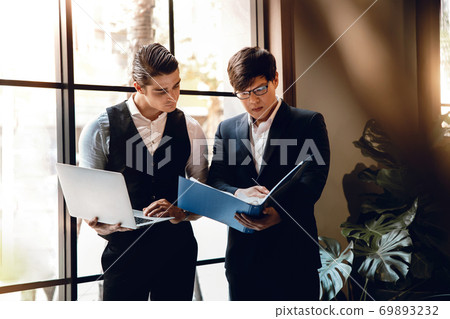 Two Businessman Working Together on Computer Laptop in Creative Workplace. 69893232