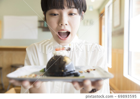 一位年輕的女大學生驚訝地在咖啡館看到可愛的蛋糕 一位年輕的女大學生驚訝地在咖啡館看到可愛的蛋糕 69893595