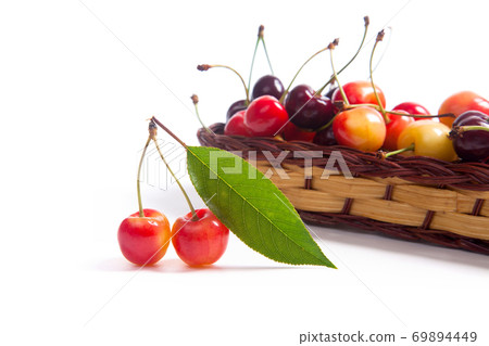 Yellow and red sweet cherry in basket with green leaf isolate on white. Yellow and red sweet cherry in basket with green leaf isolate on white. 69894449
