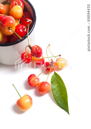 Yellow sweet cherry in white cup with green leaf isolate on white. Yellow sweet cherry in white cup with green leaf isolate on white. 69894450