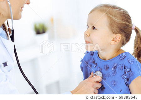 Doctor examining a little girl by stethoscope. Happy smiling child patient at usual medical inspection. Medicine and healthcare concepts Doctor examining a little girl by stethoscope. Happy smiling child patient at usual medical inspection. Medicine and healthcare concepts 69895645