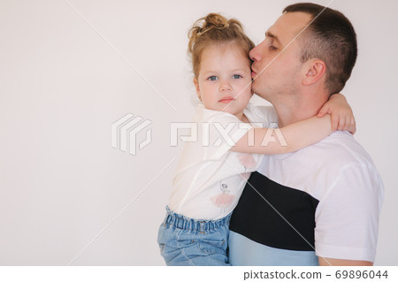 Portrait of little girl with her dad. Cute little daughter with father in studio. Dad kiss daughter in cheek 69896044