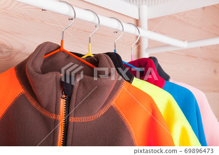 Colorful fleece jackets are hanging on hangers, close-up 69896473