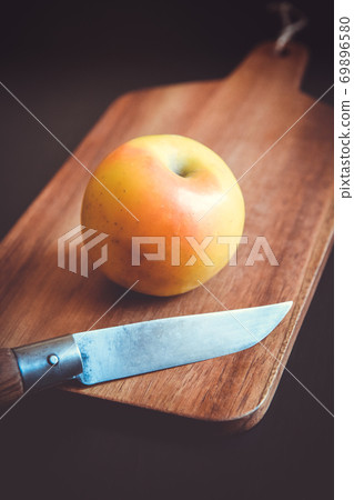 Apple and pocket knife on a wooden cutting board Apple and pocket knife on a wooden cutting board 69896580