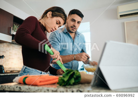Couple Cooking Together Watching Tutorial For Recipe Couple Cooking Together Watching Tutorial For Recipe 69896992