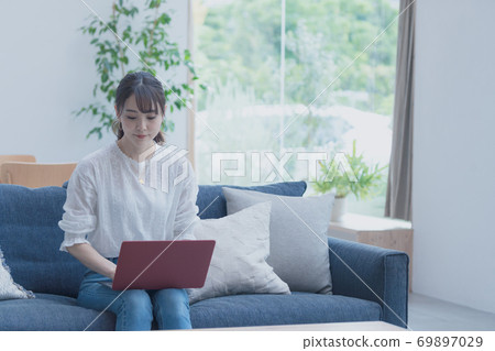 A lady who uses a laptop in the living room A lady who uses a laptop in the living room 69897029