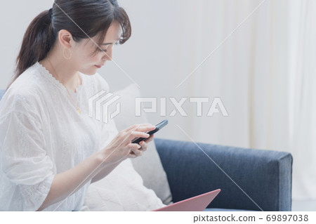 一個女人在客廳裡使用智能手機和筆記本電腦 一個女人在客廳裡使用智能手機和筆記本電腦 69897038