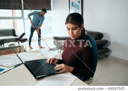 Business Woman Working At Home And Man Doing Chores Business Woman Working At Home And Man Doing Chores 69897085