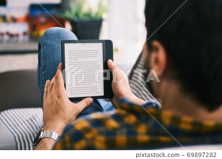 Young Man Holding Ereader And Reading Ebook Young Man Holding Ereader And Reading Ebook 69897282