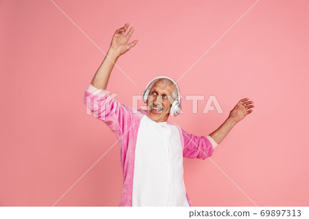 Senior hipster man in stylish pink attire isolated on pink background. Tech and joyful elderly lifestyle concept Senior hipster man in stylish pink attire isolated on pink background. Tech and joyful elderly lifestyle concept 69897313