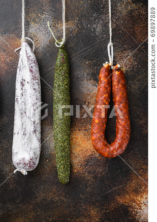 Dry cured chorizo and fuet salami sausages hanging on dark background Dry cured chorizo and fuet salami sausages hanging on dark background 69897889