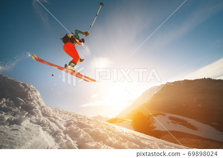 Professional athlete young male skier with a backpack and in a ski mask makes a trick in flight after jumping from a kicker on the background of a sunset 69898024