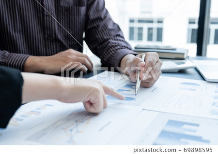 Two business leaders discussing the charts and graphs showing the results, Planning to start a new strategy for big success In the office Two business leaders discussing the charts and graphs showing the results, Planning to start a new strategy for big success In the office 69898595