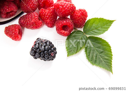 White cup with ripe raspberries with green leaf and one blackberry isolated on white background. White cup with ripe raspberries with green leaf and one blackberry isolated on white background. 69899831