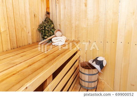 Interior details Finnish sauna steam room with traditional sauna accessories basin birch broom scoop felt hat towel. Traditional old Russian bathhouse SPA Concept. Relax country village bath concept. Interior details Finnish sauna steam room with traditional sauna accessories basin birch broom scoop felt hat towel. Traditional old Russian bathhouse SPA Concept. Relax country village bath concept. 69900052
