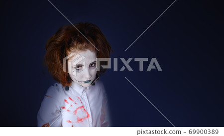 Studio shot of a girl dressed as a zombie , piercing look., halloween background. 69900389