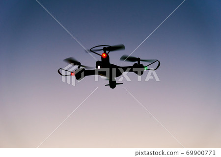 Toy drone quad copter against sunset sky 69900771