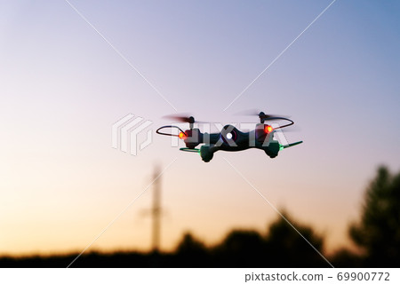 Toy drone quad copter against sunset sky 69900772