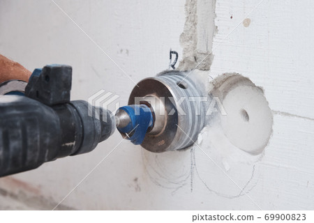 Builder with hummer drill perforator drills hole in a wall 69900823