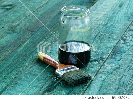 Brush and jar of paint on wooden board 69902022