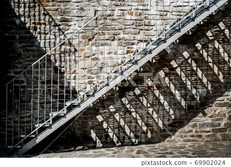 Metal stairs on stone wall 69902024