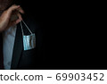 The man takes a disposable medical mask out of his pocket instead of a napkin. A man with a disposable mask in a suit. Respiratory protection. 69903452