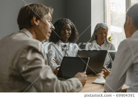 Fun business meeting of the office staff. Colleagues sit at a desk with laptops. High quality photo Fun business meeting of the office staff. Colleagues sit at a desk with laptops. High quality photo 69904391