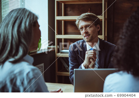 Brainstorming team of office staff. Man with glasses has a discussion with colleagues at his desk. High quality photo Brainstorming team of office staff. Man with glasses has a discussion with colleagues at his desk. High quality photo 69904404