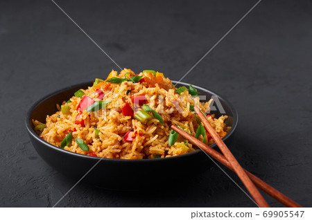 Veg Schezwan Fried Rice in black bowl at dark slate background. indo-chinese cuisine dish Veg Schezwan Fried Rice in black bowl at dark slate background. indo-chinese cuisine dish 69905547