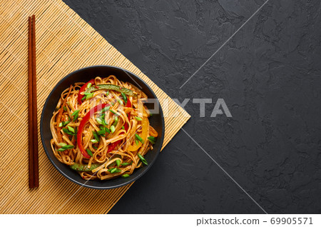Vegetarian Schezwan Noodles or Vegetable Hakka Noodles or Chow Mein in black bowl on slate table . Vegetarian Schezwan Noodles or Vegetable Hakka Noodles or Chow Mein in black bowl on slate table . 69905571