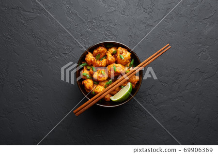 Gobi Manchurian in bowl at black concrete background. Indian Chinese cuisine dish with deep-fried cauliflower Gobi Manchurian in bowl at black concrete background. Indian Chinese cuisine dish with deep-fried cauliflower 69906369