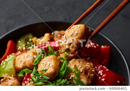 Schezwan Chicken or Dragon Chicken in black bowl at dark slate background. Schezwan Chicken or Dragon Chicken in black bowl at dark slate background. 69906401