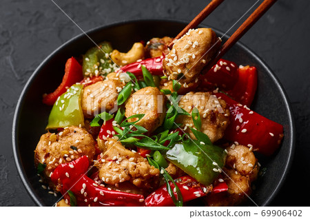 Schezwan Chicken or Dragon Chicken in black bowl at dark slate background. 69906402