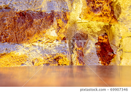 the edge of metallic table and damaged weathered burnt brick building wall with artificial moody warm light background the edge of metallic table and damaged weathered burnt brick building wall with artificial moody warm light background 69907346