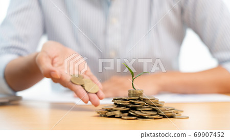 Hands of businessman putting coin into plant sprouting growing up to profit, demonstrating financial growth through saving plans and investment schemes. Hands of businessman putting coin into plant sprouting growing up to profit, demonstrating financial growth through saving plans and investment schemes. 69907452