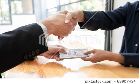 Businessman reciving money United States Dollars bills to corruption from his partner in business at working desk - bribery concept. Businessman reciving money United States Dollars bills to corruption from his partner in business at working desk - bribery concept. 69907454