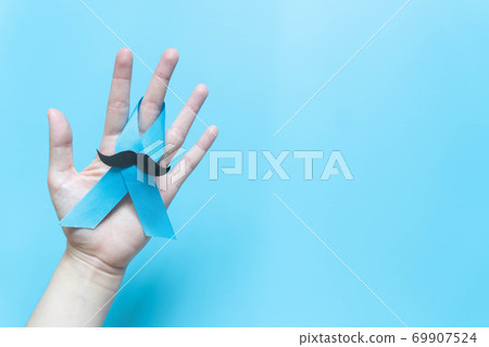 Men's health and Prostate cancer awareness campaign in November. Man hands holding light blue ribbon awareness w/ mustache on blue background. Symbol for support men who living w/ cancer. Copy space. Men's health and Prostate cancer awareness campaign in November. Man hands holding light blue ribbon awareness w/ mustache on blue background. Symbol for support men who living w/ cancer. Copy space. 69907524