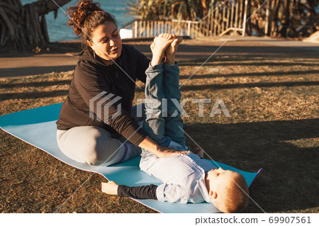 Mother and son doing gymnastics and stretching in the city park on sunset Mother and son doing gymnastics and stretching in the city park on sunset 69907561