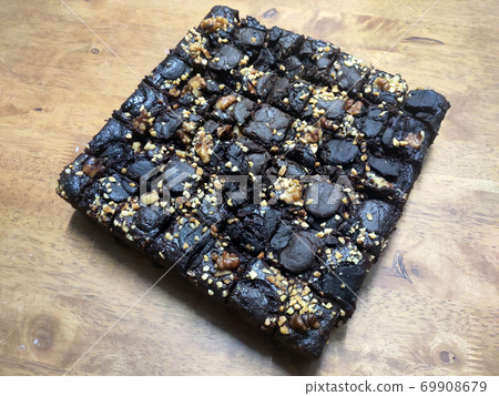 Selected focused on the chocolate cake. Rectangular in shape. Crushed almonds are sprinkled on it. Has been cut into small cubes to make it easier to eat. Selected focused on the chocolate cake. Rectangular in shape. Crushed almonds are sprinkled on it. Has been cut into small cubes to make it easier to eat. 69908679