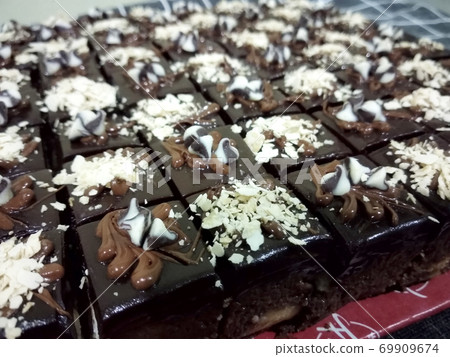 Selected focused on the chocolate & cheese cake. Rectangular in shape. Has been cut into small cubes to make it easier to eat. Selected focused on the chocolate & cheese cake. Rectangular in shape. Has been cut into small cubes to make it easier to eat. 69909674
