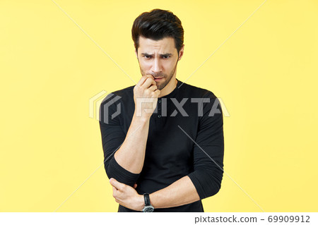Serious houghtful man have a doubt over yellow background 69909912