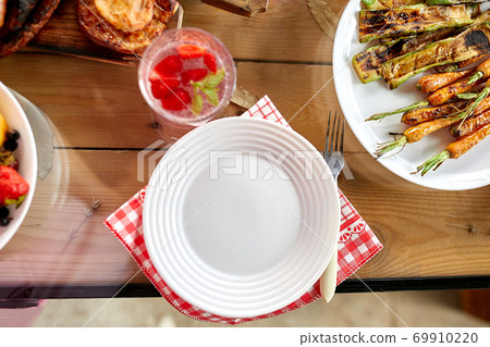 Dinner table with meat grill, roast vegetables, sauces and lemonade, variety serving 69910220